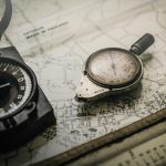 shallow focus photography of black and silver compasses on top of map